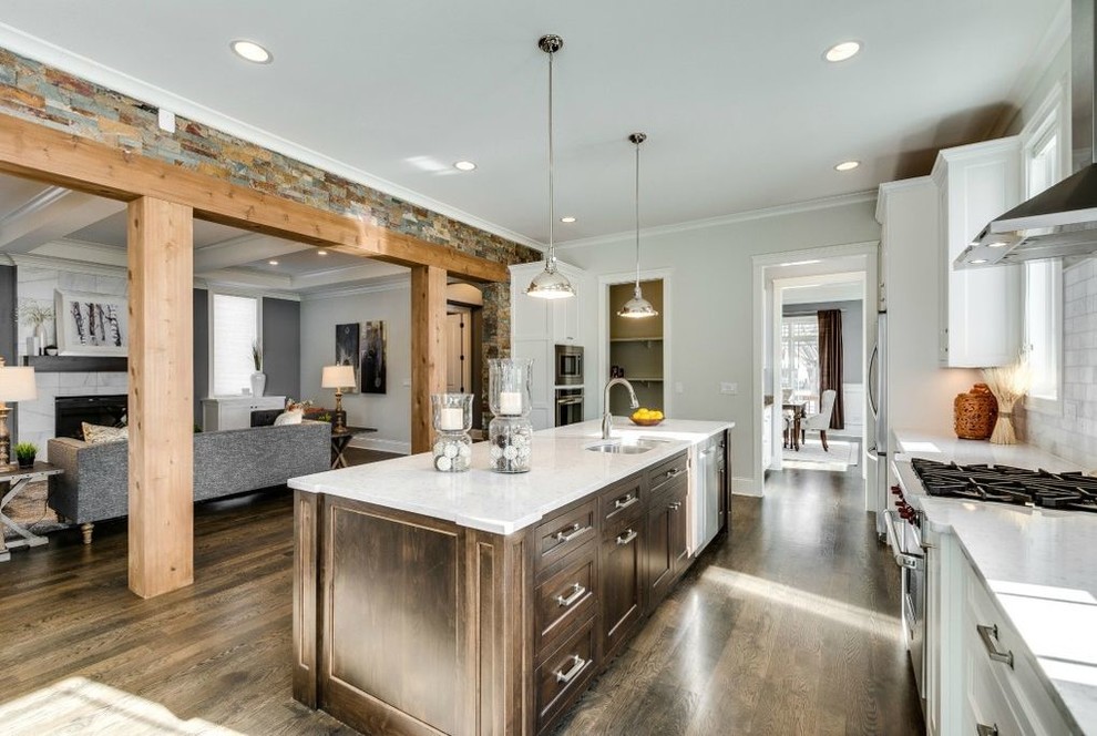 Inspiration for a large traditional single-wall eat-in kitchen in Chicago with an undermount sink, recessed-panel cabinets, white cabinets, granite benchtops, grey splashback, porcelain splashback, stainless steel appliances, medium hardwood floors, with island, brown floor and white benchtop.