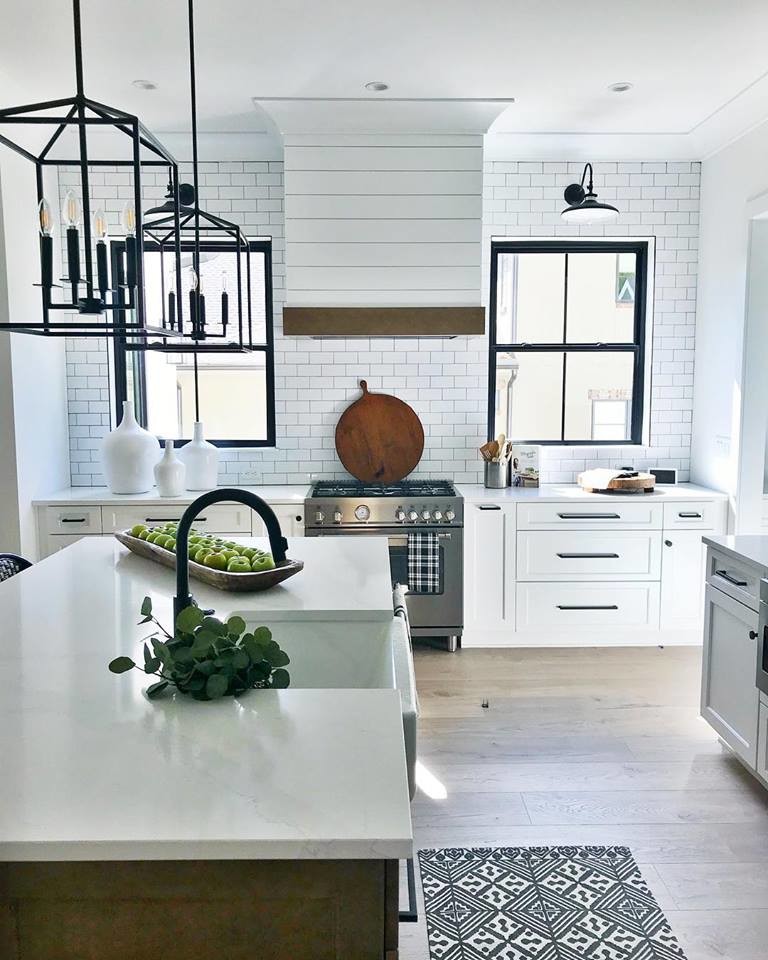 This is an example of a mid-sized country l-shaped eat-in kitchen in Charlotte with a farmhouse sink, recessed-panel cabinets, white cabinets, quartz benchtops, white splashback, subway tile splashback, stainless steel appliances, light hardwood floors, with island, beige floor and white benchtop.