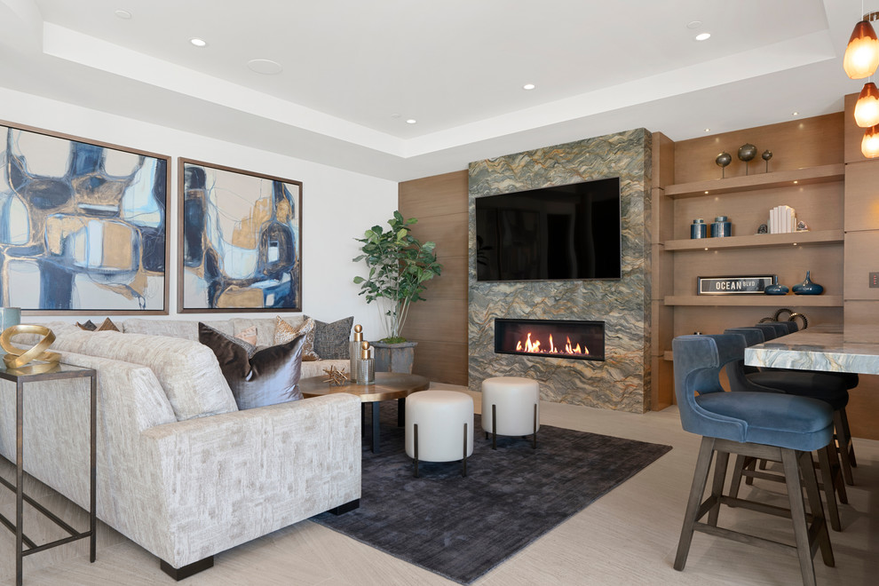 Design ideas for a contemporary open concept family room in Orange County with white walls, a ribbon fireplace, a stone fireplace surround, a wall-mounted tv, beige floor and limestone floors.