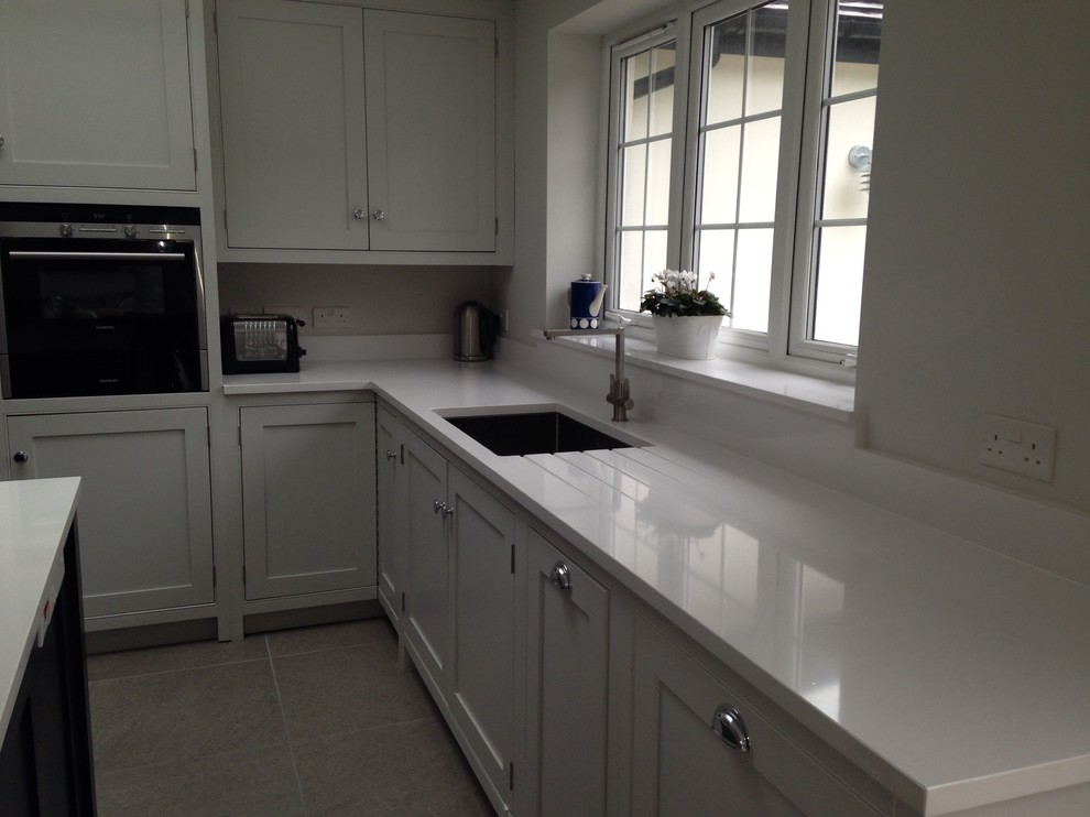 Photo of a large contemporary l-shaped kitchen in Surrey with beaded inset cabinets, grey cabinets, with island, grey floor and white benchtop.