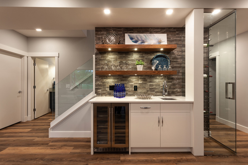 Mid-sized transitional single-wall wet bar in Calgary with an undermount sink, open cabinets, brown cabinets, quartzite benchtops, grey splashback, stone tile splashback, vinyl floors, brown floor and white benchtop.