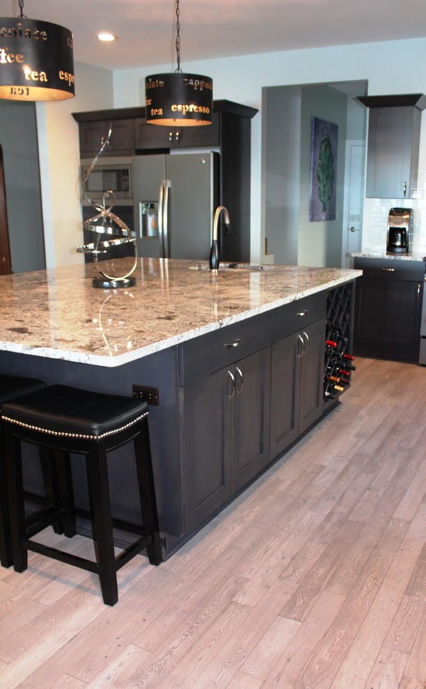 Inspiration for an expansive eclectic l-shaped open plan kitchen in Detroit with an undermount sink, flat-panel cabinets, dark wood cabinets, granite benchtops, blue splashback, glass tile splashback, stainless steel appliances, with island and brown benchtop.