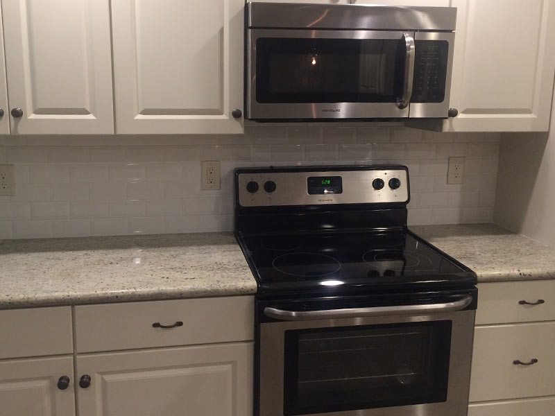 Kitchen - kitchen idea with recessed-panel cabinets, white cabinets, granite countertops, white backsplash, subway tile backsplash and stainless steel appliances