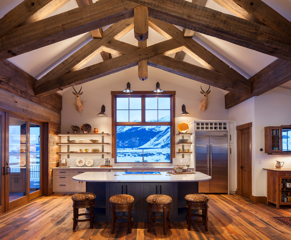 Mountain style galley dark wood floor and brown floor open concept kitchen photo in Denver with an undermount sink, shaker cabinets, white cabinets, stainless steel appliances, an island and white countertops