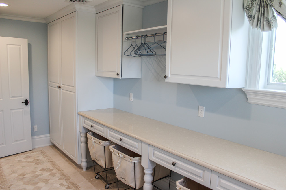 Inspiration for a large traditional galley utility room in New York with a drop-in sink, white cabinets, blue walls, ceramic floors, a side-by-side washer and dryer and raised-panel cabinets.