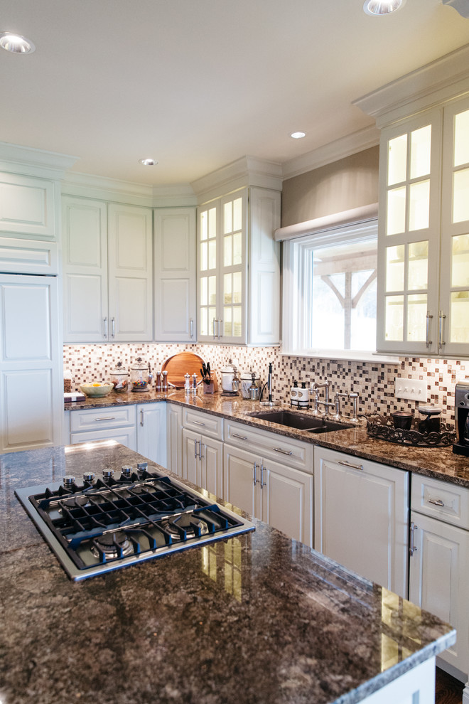 Inspiration for a traditional l-shaped open plan kitchen in Nashville with a double-bowl sink, raised-panel cabinets, white cabinets, granite benchtops, mosaic tile splashback, panelled appliances, medium hardwood floors and with island.