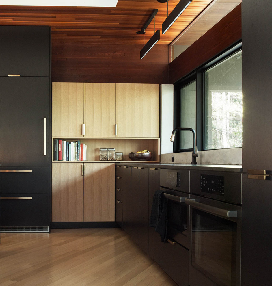 Foto di una grande cucina moderna con lavello sottopiano, ante lisce, ante nere, top in granito, paraspruzzi grigio, elettrodomestici neri, parquet chiaro, top nero e soffitto in legno