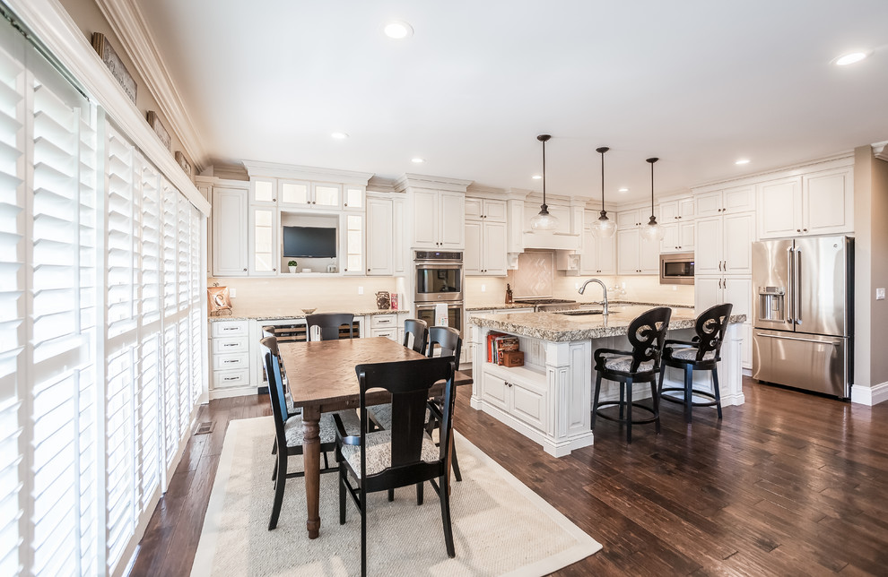 Inspiration for a large transitional l-shaped kitchen remodel in St Louis with an undermount sink, raised-panel cabinets, white cabinets, granite countertops, beige backsplash, subway tile backsplash, stainless steel appliances and an island