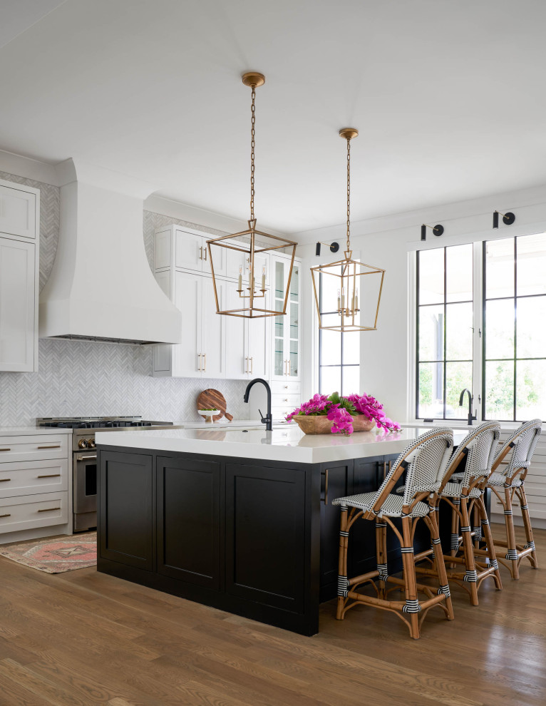 This is an example of a large transitional u-shaped eat-in kitchen in Dallas with an undermount sink, shaker cabinets, white cabinets, quartz benchtops, white splashback, marble splashback, white appliances, medium hardwood floors, with island, brown floor and white benchtop.