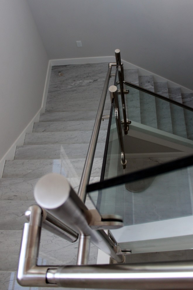 Foto de escalera minimalista con escalones de mármol, contrahuellas de madera y barandilla de metal