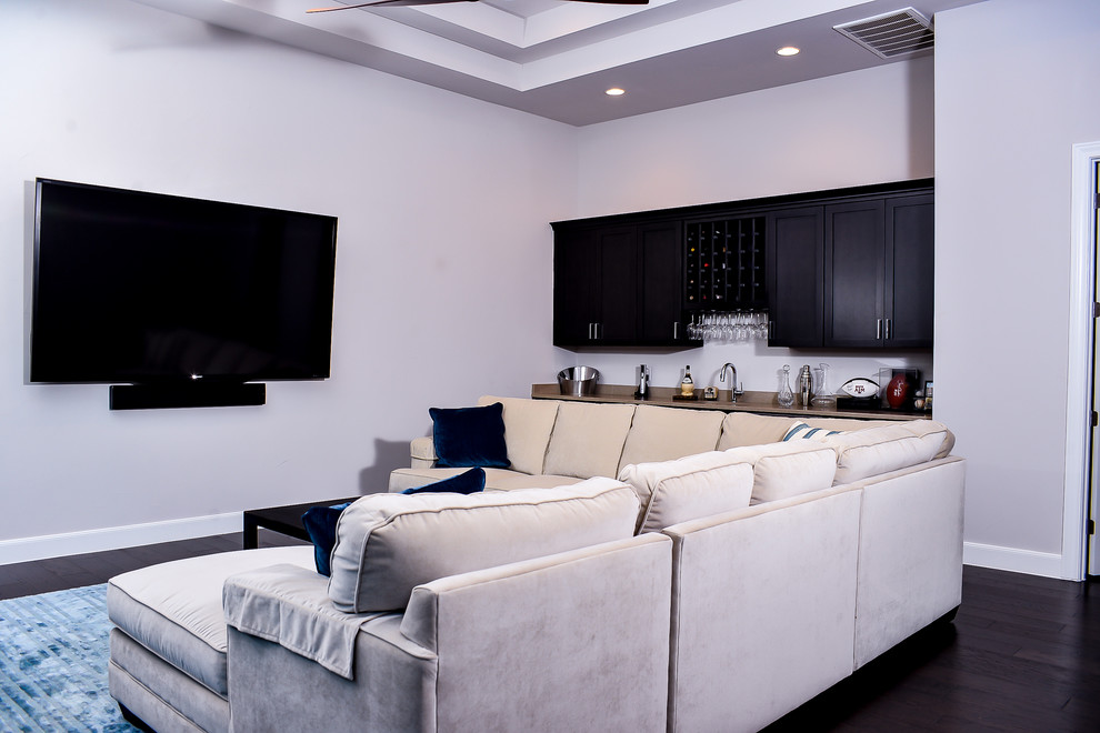 This is an example of a large transitional enclosed home theatre in Austin with grey walls, dark hardwood floors, a wall-mounted tv and brown floor.