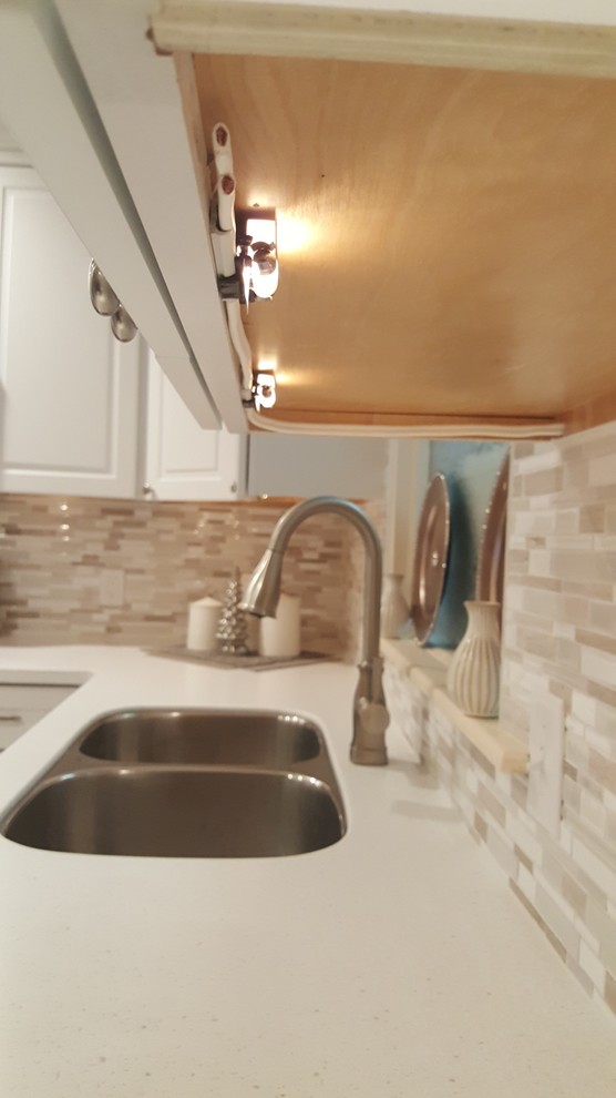 Eat-in kitchen - small l-shaped eat-in kitchen idea with an undermount sink, raised-panel cabinets, white cabinets, quartz countertops, white backsplash, porcelain backsplash, stainless steel appliances and no island