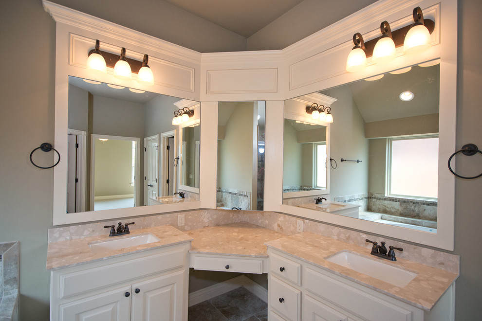 Inspiration for a mid-sized transitional master bathroom in Oklahoma City with an integrated sink, raised-panel cabinets, white cabinets, marble benchtops, a drop-in tub, brown tile, ceramic tile, beige walls, a corner shower, a one-piece toilet and ceramic floors.