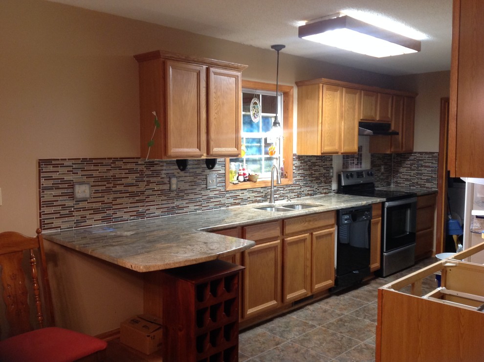 Inspiration for a l-shaped eat-in kitchen remodel with an undermount sink, flat-panel cabinets, brown backsplash, glass tile backsplash, stainless steel appliances and a peninsula