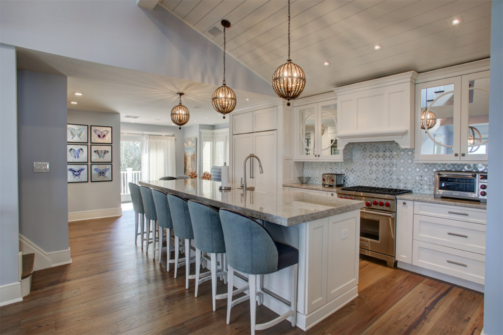 Transitional l-shaped kitchen in Other with a farmhouse sink, shaker cabinets, white cabinets, blue splashback, stainless steel appliances, medium hardwood floors, with island, brown floor and grey benchtop.