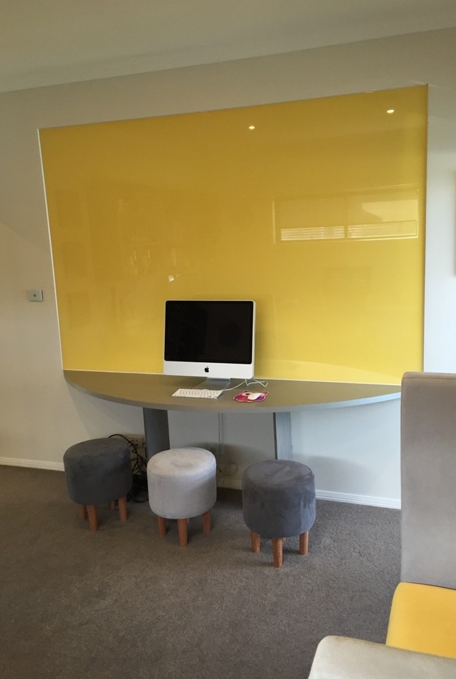 This is an example of a mid-sized contemporary study room in Sydney with white walls, carpet, a built-in desk and grey floor.