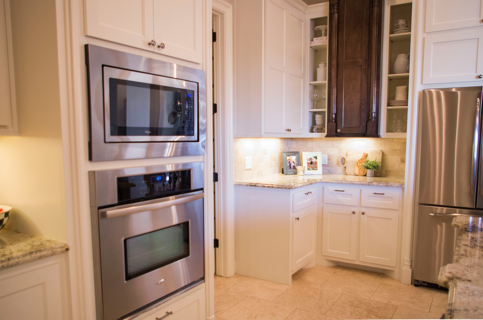 Elegant travertine floor kitchen photo in Austin with a drop-in sink, flat-panel cabinets, medium tone wood cabinets, granite countertops, stainless steel appliances and an island
