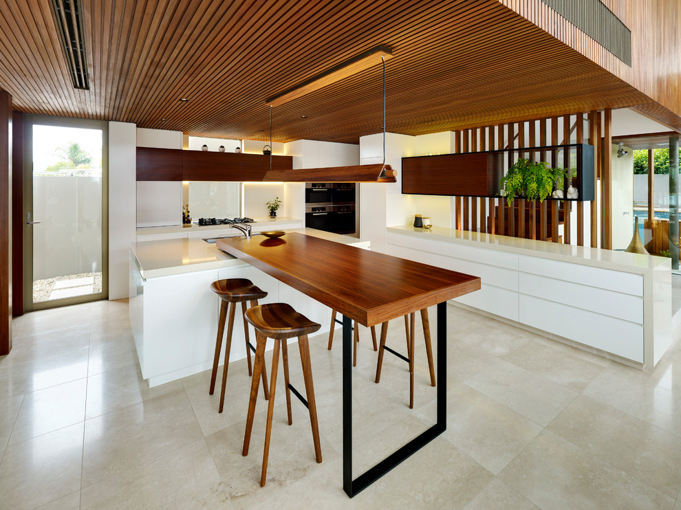 This is an example of a contemporary l-shaped kitchen in Sydney with flat-panel cabinets, white cabinets, multiple islands, beige floor and beige benchtop.
