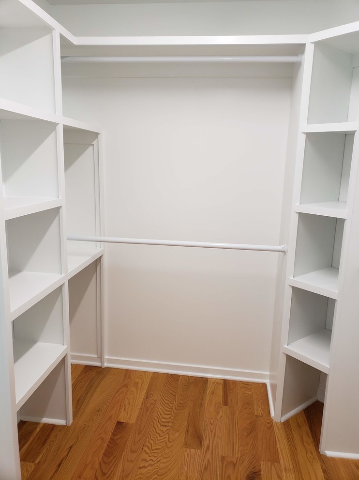 Inspiration for a mid-sized contemporary gender-neutral walk-in wardrobe in Raleigh with open cabinets, white cabinets, medium hardwood floors and brown floor.