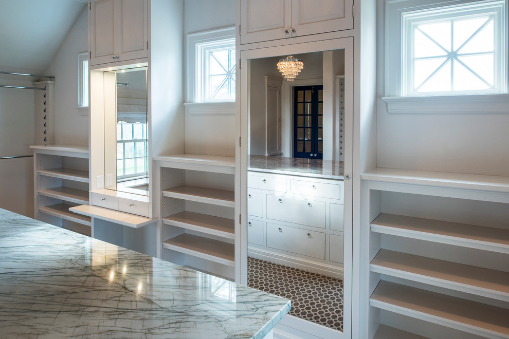 This is an example of a large contemporary gender-neutral walk-in wardrobe in Cincinnati with raised-panel cabinets, white cabinets and brown floor.