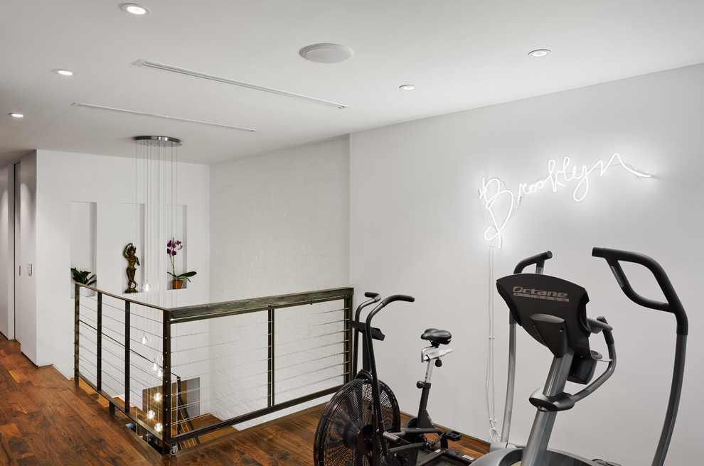 Contemporary home gym in New York with white walls and dark hardwood floors.