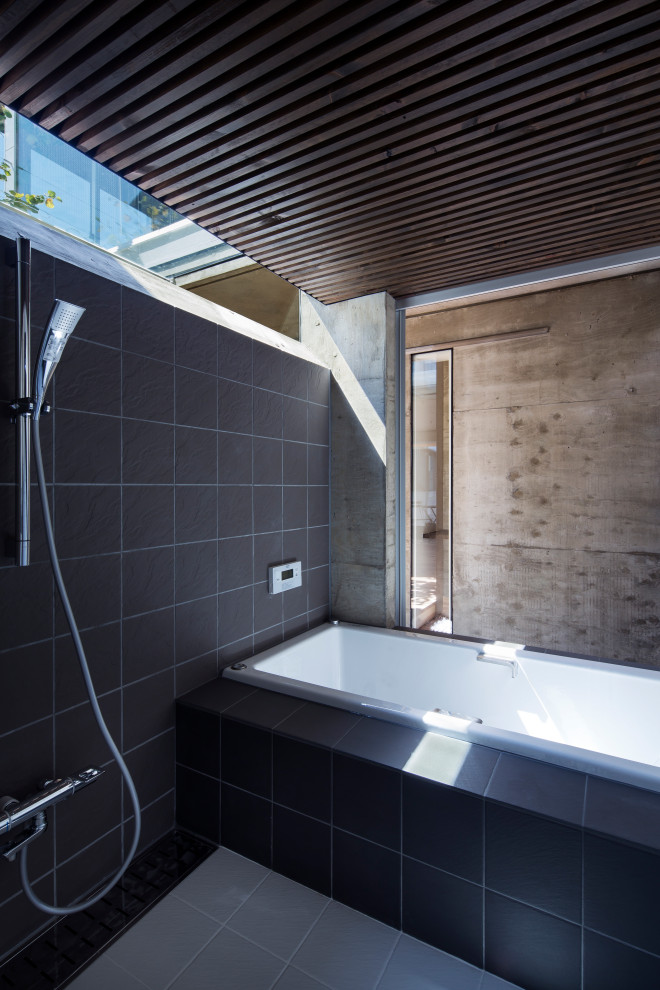 Пример оригинального дизайна: ванная комната с накладной ванной, черной плиткой, керамогранитной плиткой, серыми стенами, полом из керамогранита, серым полом, окном и кессонным потолком