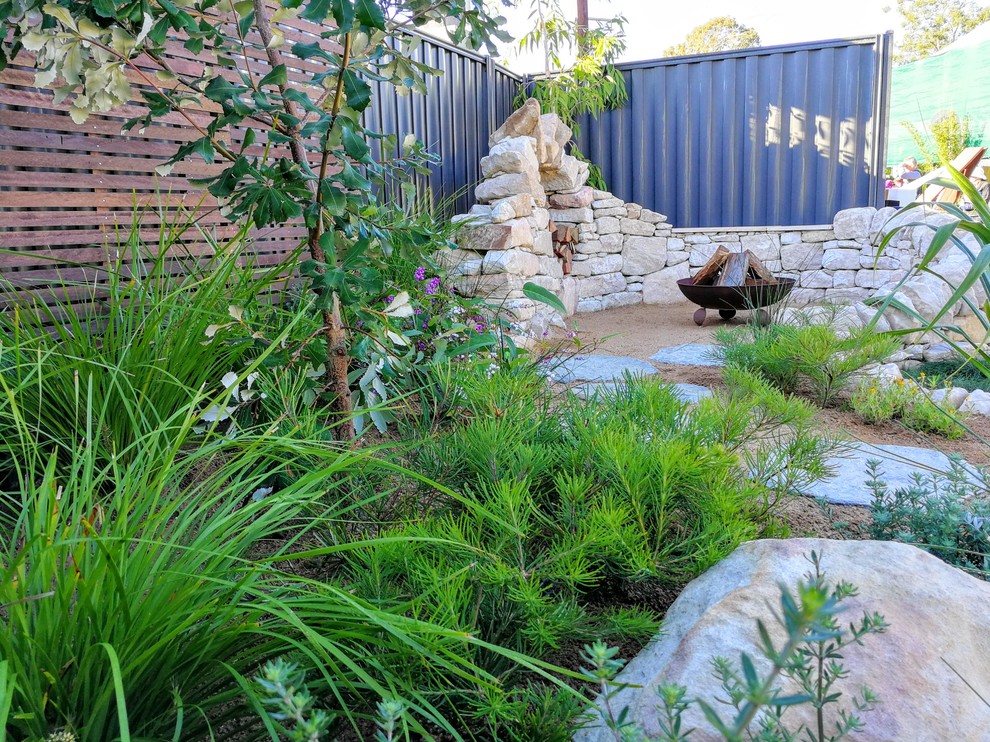 Design ideas for a small and australian native beach style full sun xeriscape in Sunshine Coast with a retaining wall and natural stone pavers.