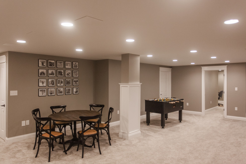 Large traditional look-out basement in Cincinnati with a home bar, beige walls, laminate floors, brown floor and decorative wall panelling.