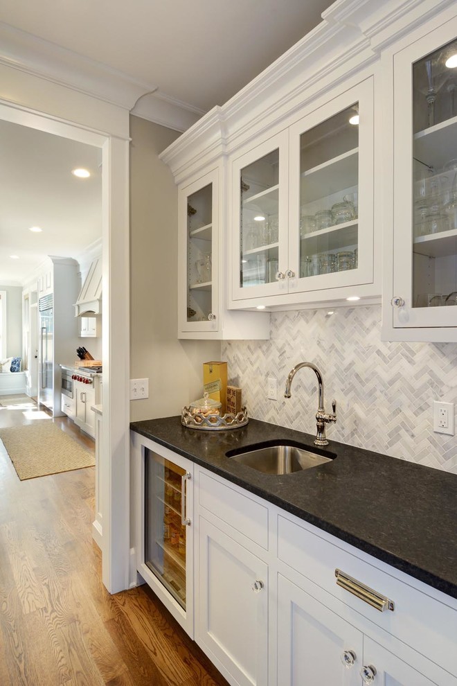 This is an example of a large transitional u-shaped eat-in kitchen in Boston with a farmhouse sink, flat-panel cabinets, white cabinets, quartzite benchtops, white splashback, ceramic splashback, stainless steel appliances, medium hardwood floors and with island.