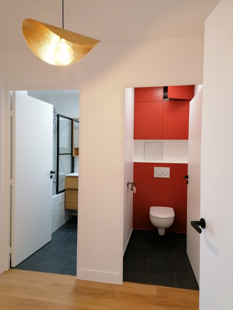 Пример оригинального дизайна: туалет среднего размера в стиле лофт с плоскими фасадами, красными фасадами, инсталляцией, белыми стенами, полом из керамической плитки, черным полом и подвесной тумбой