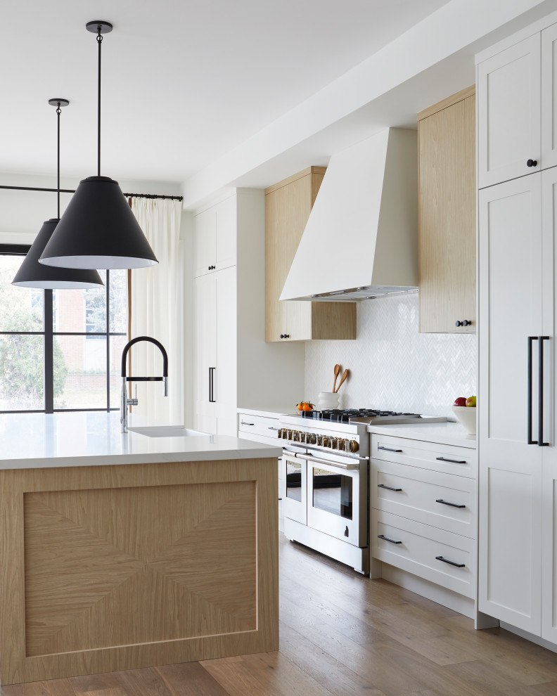 Large transitional single-wall eat-in kitchen in Toronto with a farmhouse sink, white cabinets, white splashback, porcelain splashback, stainless steel appliances, light hardwood floors, with island, beige floor, white benchtop and shaker cabinets.