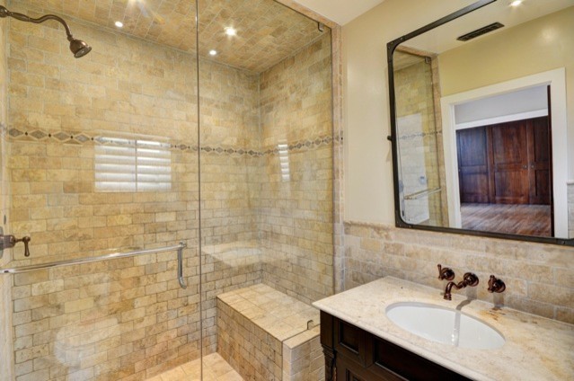 Design ideas for a mid-sized traditional 3/4 bathroom in Los Angeles with recessed-panel cabinets, dark wood cabinets, an alcove shower, a two-piece toilet, beige tile, stone tile, beige walls, travertine floors, an undermount sink, granite benchtops and a sliding shower screen.