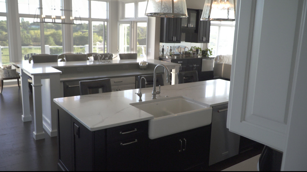 Inspiration for a transitional l-shaped medium tone wood floor and brown floor eat-in kitchen remodel with a farmhouse sink, shaker cabinets, white cabinets, quartz countertops, white backsplash, marble backsplash, stainless steel appliances and two islands