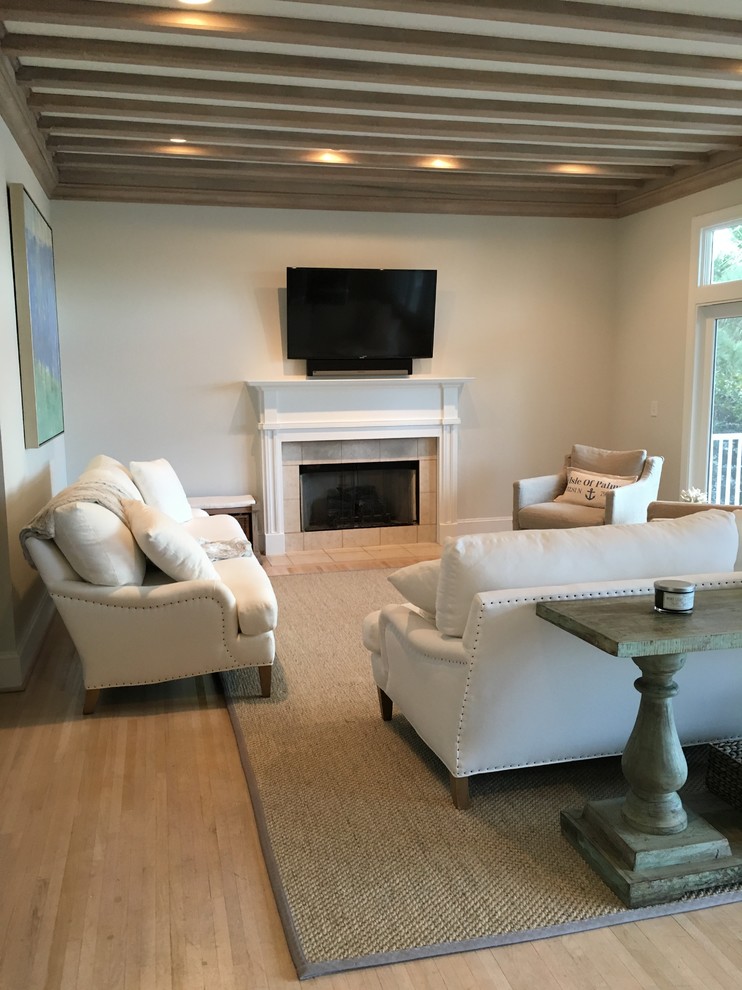 Inspiration for a mid-sized contemporary open concept family room in Charleston with beige walls, light hardwood floors, a standard fireplace, a tile fireplace surround and a freestanding tv.