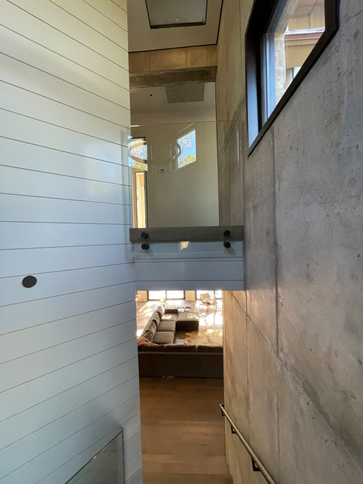Источник вдохновения для домашнего уюта: лестница на больцах, среднего размера в современном стиле с деревянными ступенями, стеклянными перилами и стенами из вагонки без подступенок