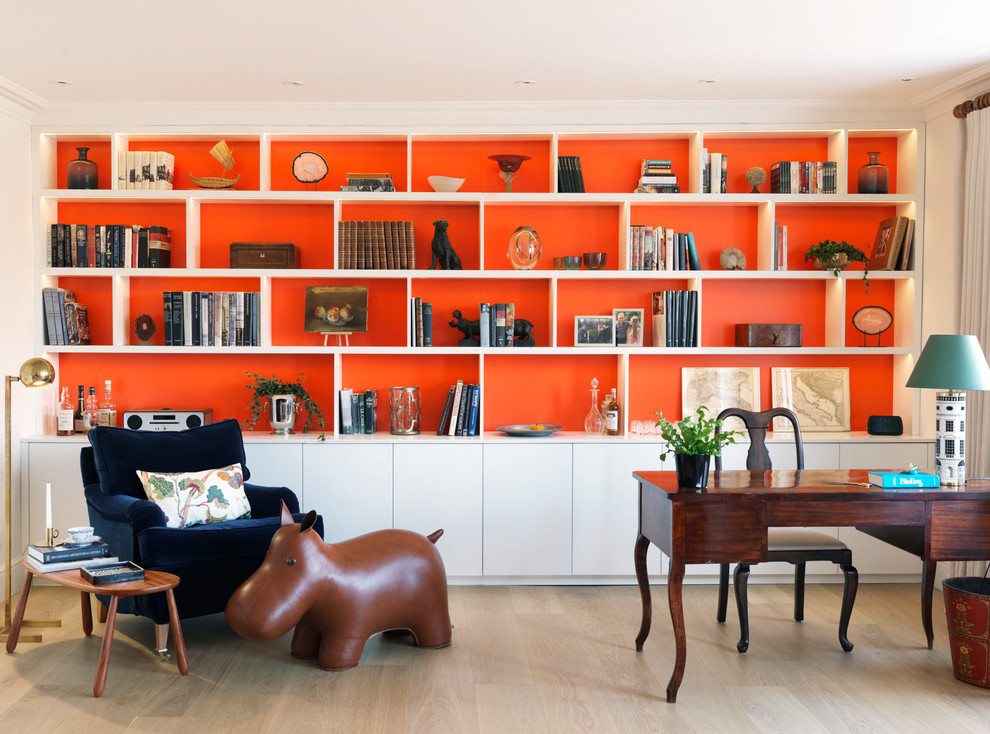 Inspiration for an eclectic home office in London with a library, orange walls, a freestanding desk and beige floor.