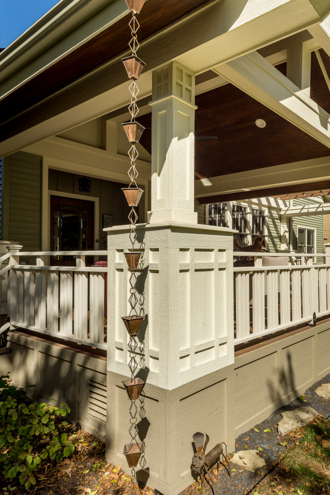 Aménagement d'un grand porche d'entrée de maison avant craftsman avec une moustiquaire, des pavés en pierre naturelle, une extension de toiture et un garde-corps en verre.