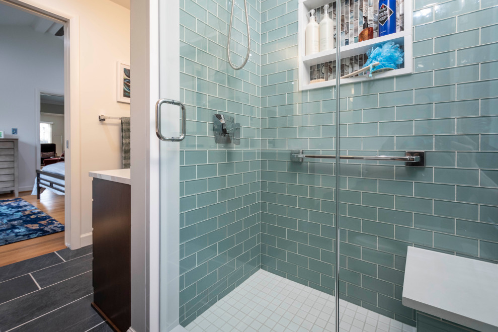 This is an example of a mid-sized modern master bathroom in Indianapolis with flat-panel cabinets, medium wood cabinets, an alcove shower, a one-piece toilet, white tile, subway tile, white walls, porcelain floors, an undermount sink, engineered quartz benchtops, grey floor, a hinged shower door, white benchtops, a shower seat, a double vanity and a floating vanity.