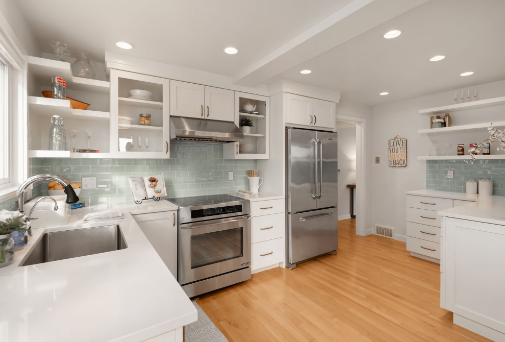 Design ideas for a large transitional u-shaped kitchen in Seattle with an undermount sink, flat-panel cabinets, white cabinets, grey splashback, subway tile splashback, stainless steel appliances, beige floor and white benchtop.