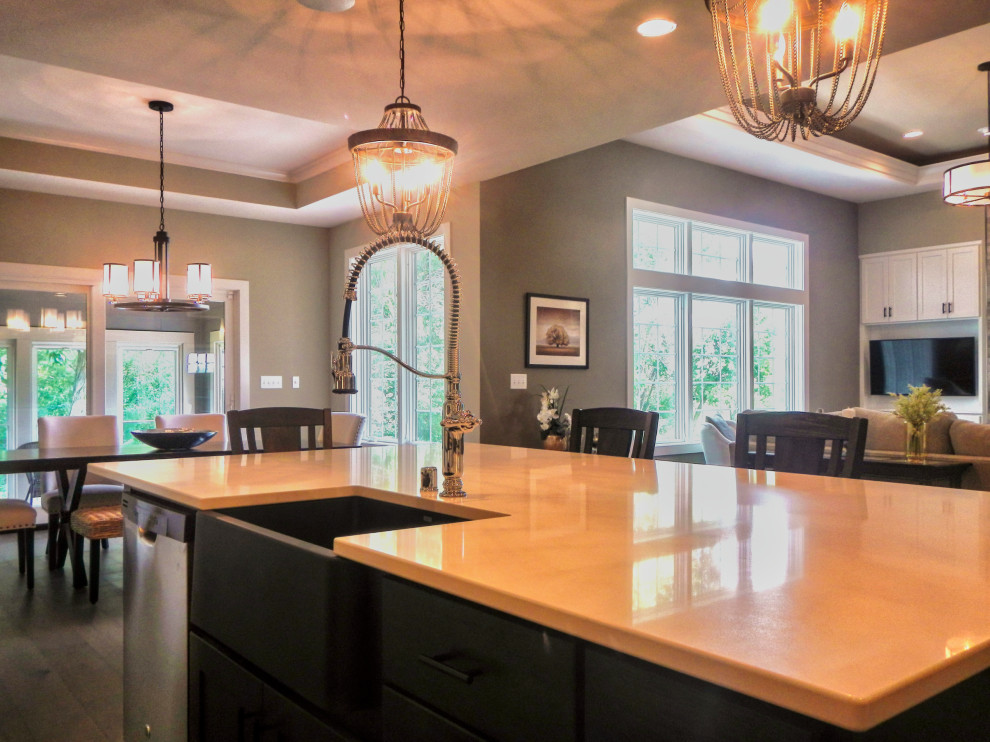 Example of a mid-sized transitional l-shaped medium tone wood floor and brown floor open concept kitchen design with a farmhouse sink, shaker cabinets, dark wood cabinets, quartz countertops, stainless steel appliances and an island