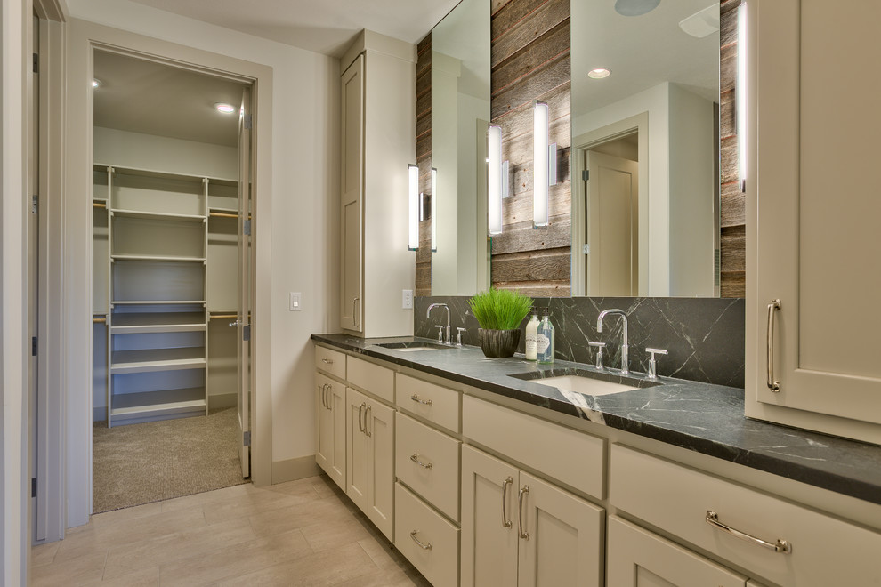 This is an example of a mid-sized country master bathroom in Omaha with flat-panel cabinets, grey cabinets, an open shower, a one-piece toilet, white tile, ceramic tile, white walls, ceramic floors, an undermount sink and soapstone benchtops.