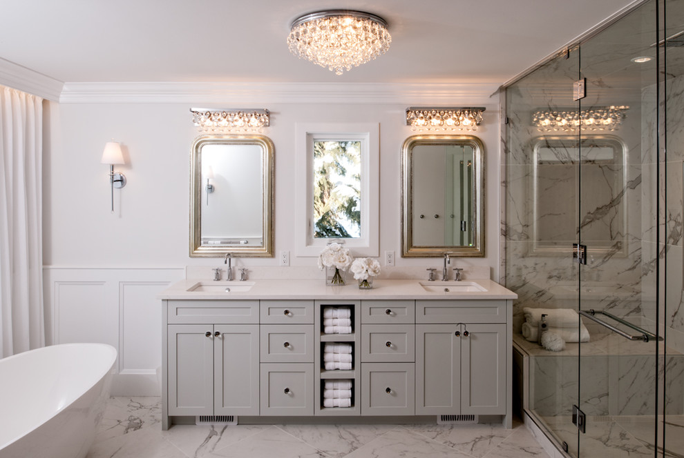 This is an example of a traditional bathroom in Calgary with shaker cabinets, grey cabinets, a freestanding tub, an alcove shower, white walls, an undermount sink and a hinged shower door.
