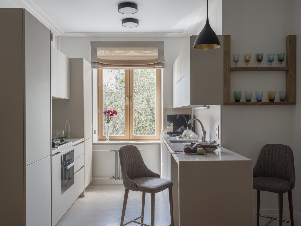 This is an example of a small contemporary galley separate kitchen in Moscow with an undermount sink, flat-panel cabinets, a peninsula, beige floor, beige cabinets, beige splashback, panelled appliances and beige benchtop.