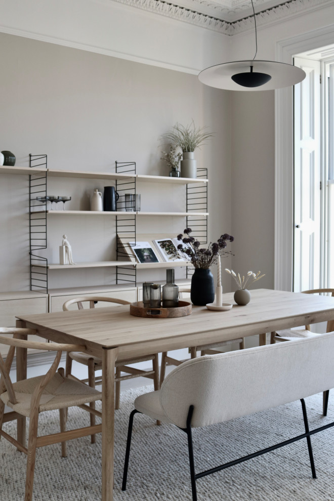 Bild på ett stort minimalistiskt vardagsrum, med beige väggar, ljust trägolv, en öppen vedspis, en spiselkrans i trä, TV i ett hörn och beiget golv