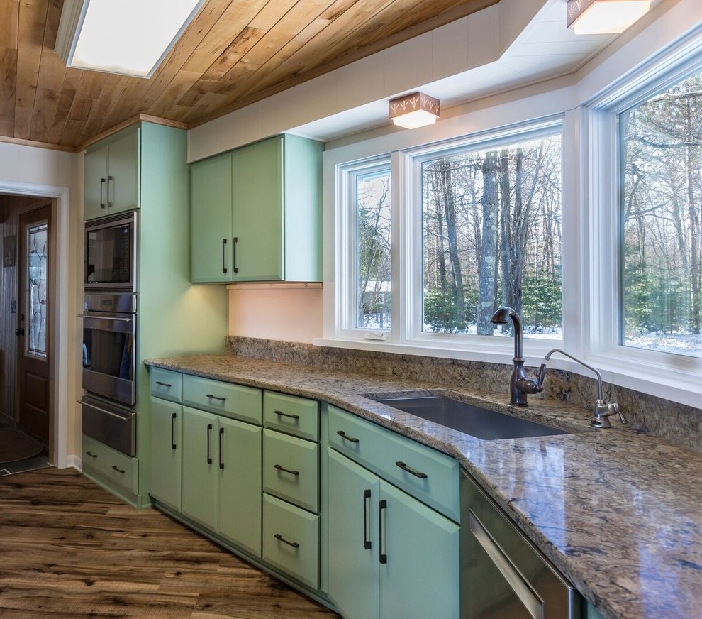 Mid-sized transitional l-shaped vinyl floor and brown floor eat-in kitchen photo with an undermount sink, flat-panel cabinets, green cabinets, quartz countertops, stainless steel appliances, a peninsula and beige countertops