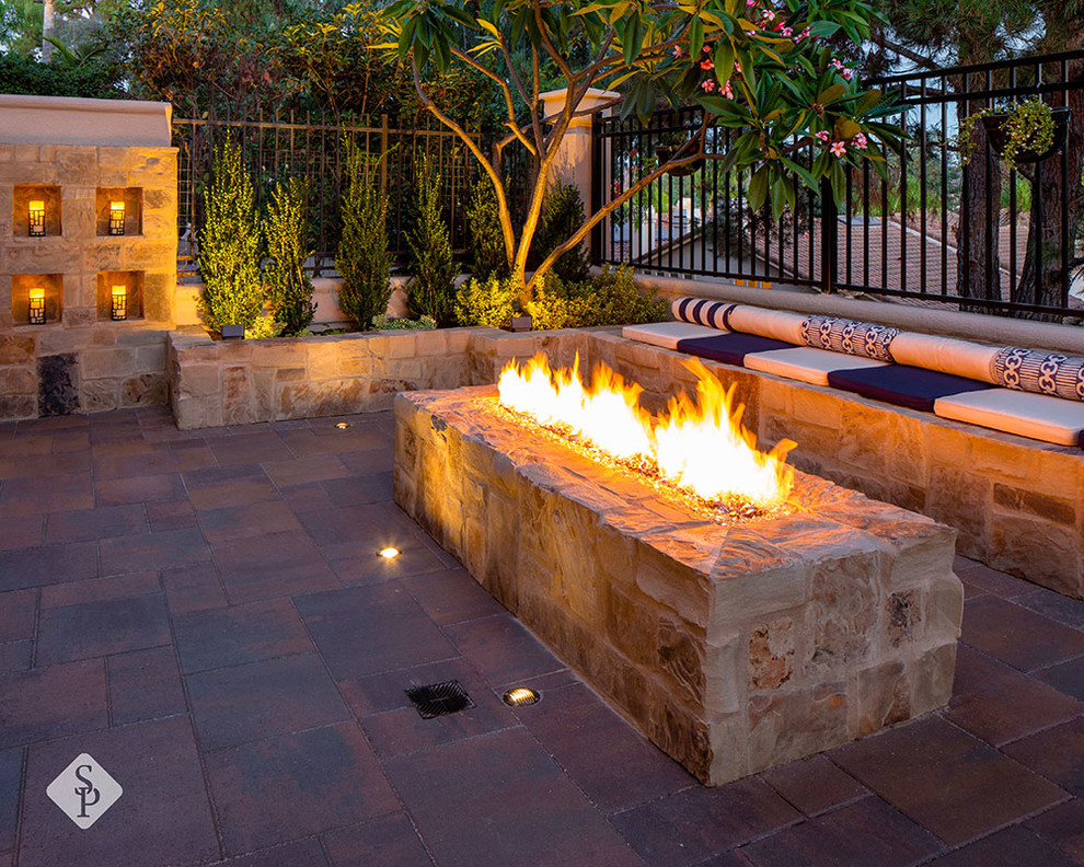 Inspiration for a mid-sized backyard patio in Orange County with a fire feature, concrete pavers and no cover.