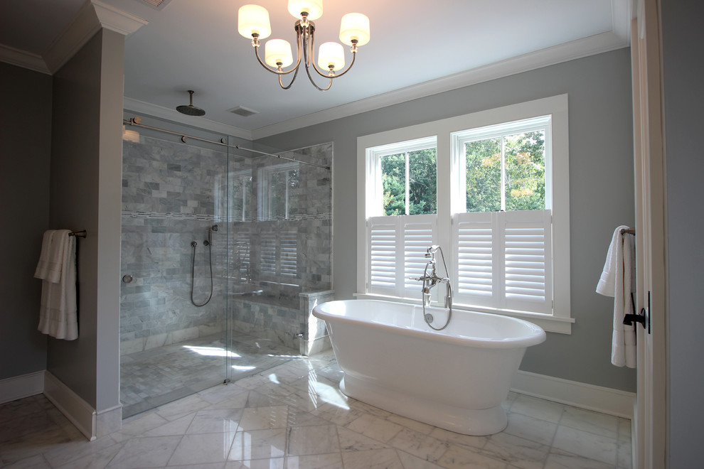 Inspiration for a mid-sized beach style master bathroom in New York with an undermount sink, flat-panel cabinets, white cabinets, marble benchtops, a freestanding tub, a curbless shower, a two-piece toilet, gray tile, stone tile, grey walls and marble floors.
