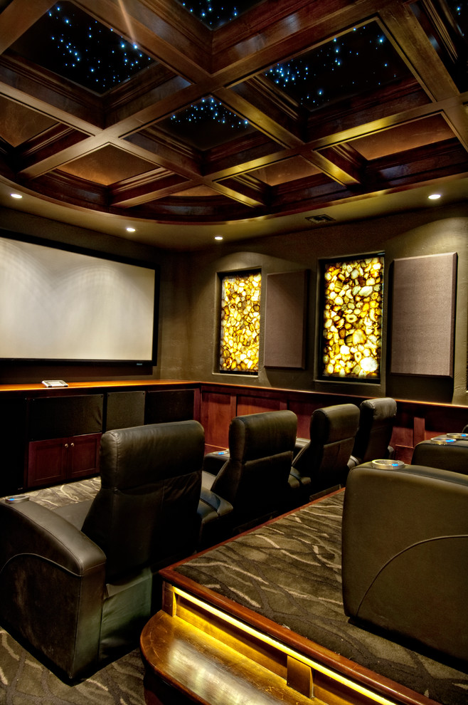 This is an example of a mediterranean enclosed home theatre in Miami with brown walls, carpet and a projector screen.
