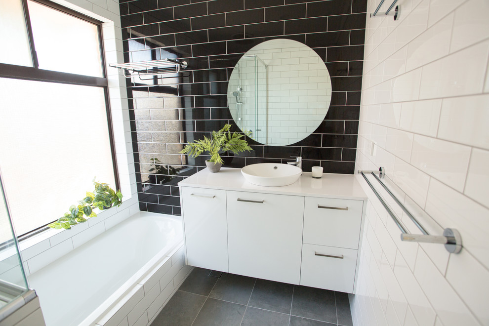Design ideas for a mid-sized modern master bathroom in Perth with white cabinets, a drop-in tub, a corner shower, black and white tile, ceramic tile, multi-coloured walls, porcelain floors, a drop-in sink, solid surface benchtops, grey floor, a hinged shower door and white benchtops.