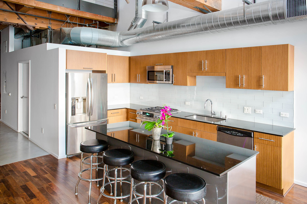 Mid-sized industrial kitchen in Los Angeles with an undermount sink, white splashback and stainless steel appliances.